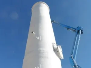 A crane is working on the side of a white tower.