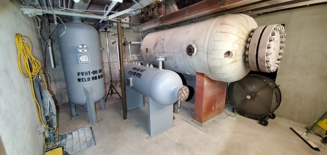 A large metal tank sitting next to two other tanks.