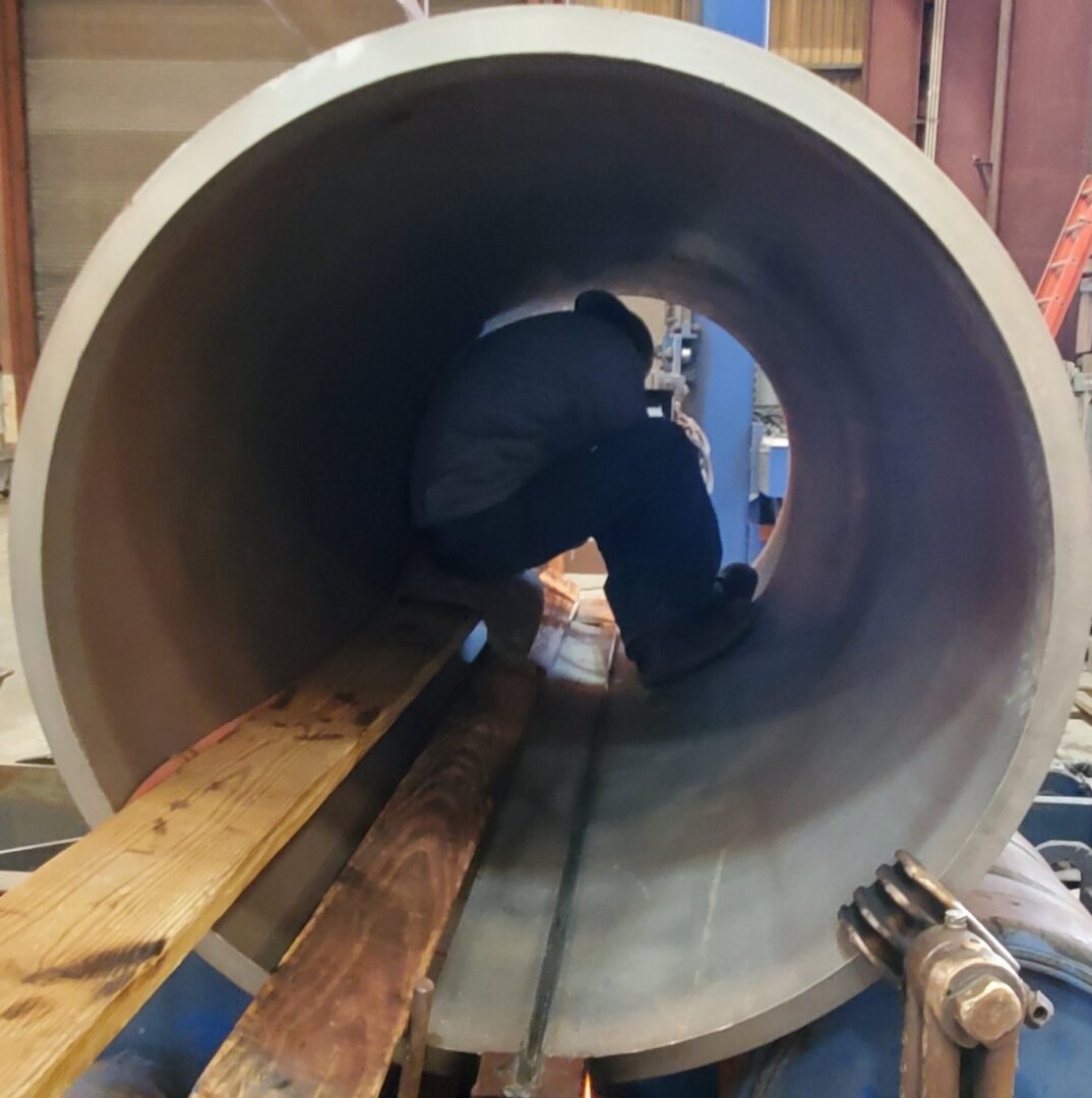 A man is working on the inside of a pipe.