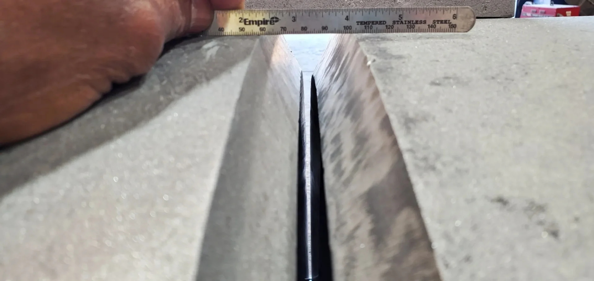 A ruler is pointing to the length of a metal object.