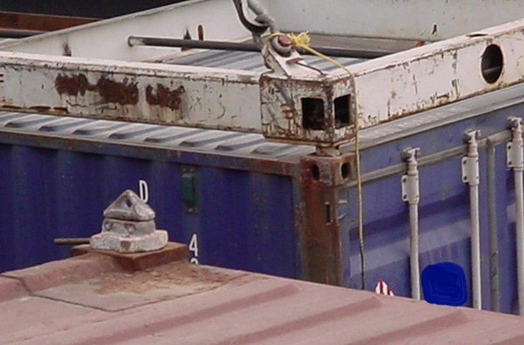 Rusty crane lifting shipping container corner