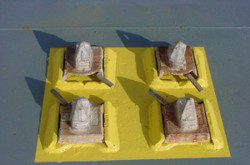 Four rusted metal studs on yellow square base