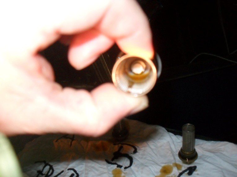 Hand holding brass plumbing valve cartridge